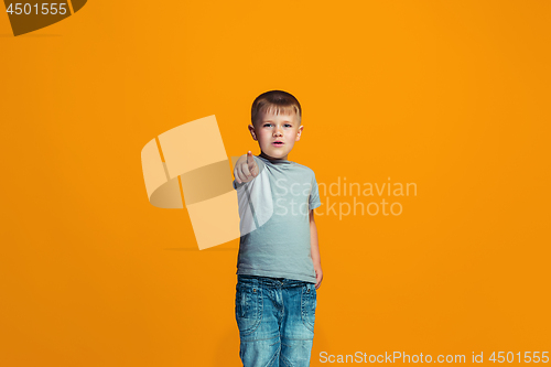 Image of The happy teen boy pointing to you, half length closeup portrait on orange background.