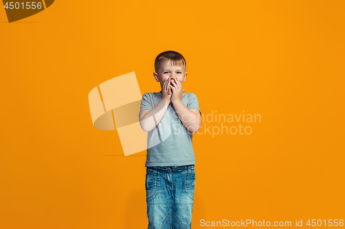 Image of The happy teen boy standing and smiling against orange background.