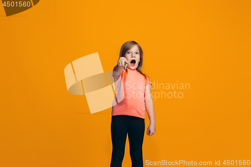 Image of The happy teen girl pointing to you, half length closeup portrait on orange background.