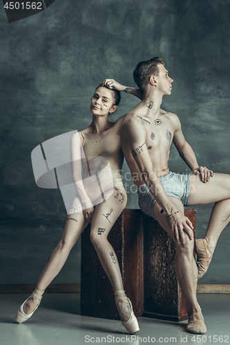 Image of The young modern ballet dancers posing on gray studio background