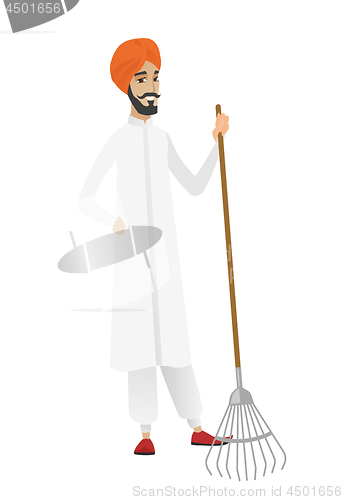 Image of Young hindu farmer holding gardening rake.