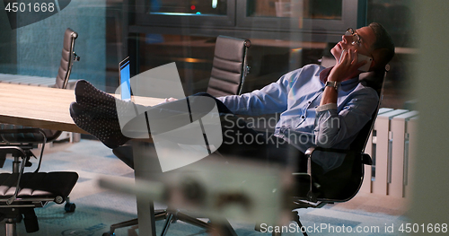 Image of businessman sitting with legs on desk at office