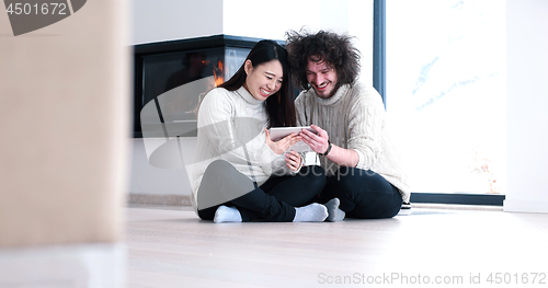 Image of Young Couple using digital tablet on the floor