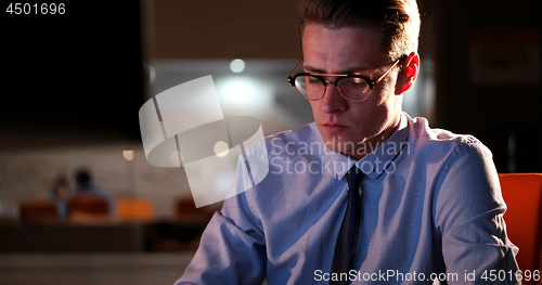 Image of man working on computer in dark office