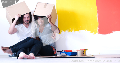 Image of young multiethnic couple playing with cardboard boxes