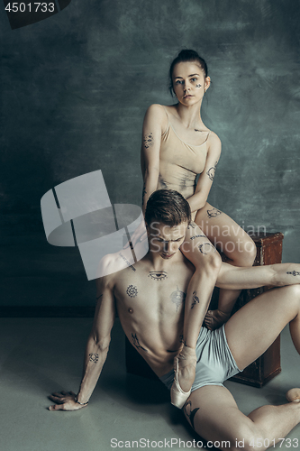 Image of The young modern ballet dancers posing on gray studio background