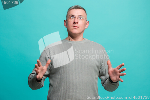 Image of The young attractive man looking suprised isolated on blue