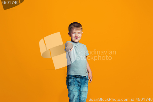 Image of The happy teen boy pointing to you, half length closeup portrait on orange background.