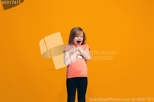 Image of The happy teen girl standing and smiling against orange background.