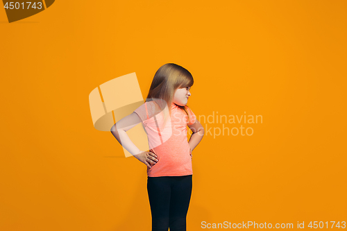 Image of Portrait of angry teen girl on a orange studio background