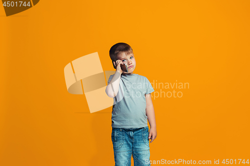 Image of The happy teen boy standing and smiling against orange background.