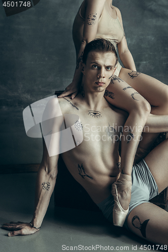 Image of The young modern ballet dancers posing on gray studio background