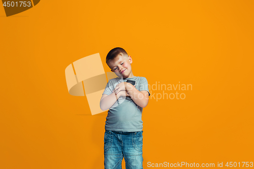 Image of The happy teen boy standing and smiling against orange background.