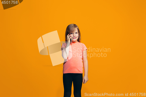 Image of The happy teen girl standing and smiling against orange background.