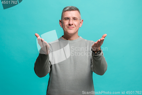Image of The happy business man standing and smiling against blue background.