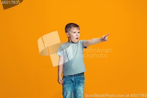 Image of The happy teen boy pointing to you, half length closeup portrait on orange background.