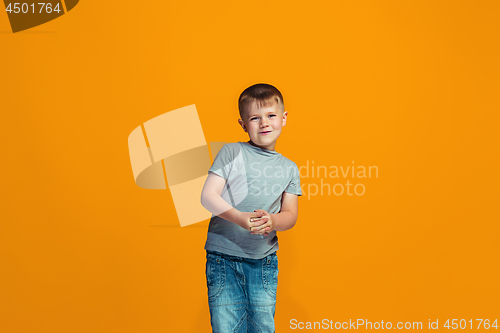 Image of The happy teen boy standing and smiling against orange background.