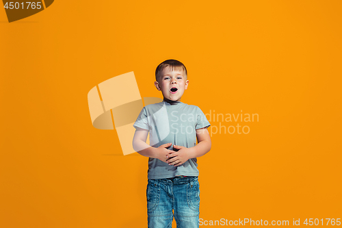 Image of The happy teen boy standing and smiling against orange background.