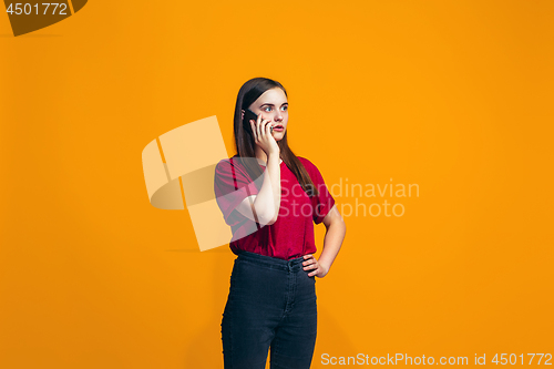 Image of The happy teen girl standing and smiling against orange background.