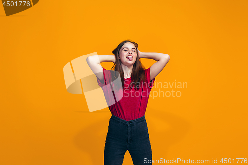 Image of The happy teen girl standing and smiling against orange background.