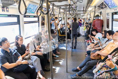 Image of Passenegers using their mobile phone devices while commuting by city metro in Bangkok, Thailand