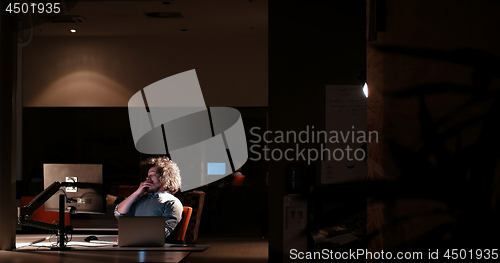 Image of man working on computer in dark office