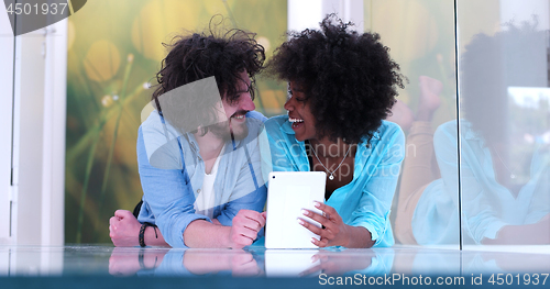 Image of Couple relaxing together at home with tablet computer