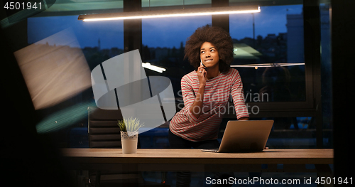 Image of black businesswoman using a laptop in night startup office