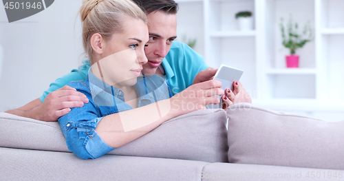 Image of couple relaxing at  home with tablet computers