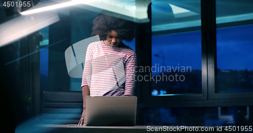 Image of black businesswoman using a laptop in night startup office