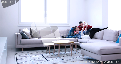 Image of couple relaxing at  home with tablet computers