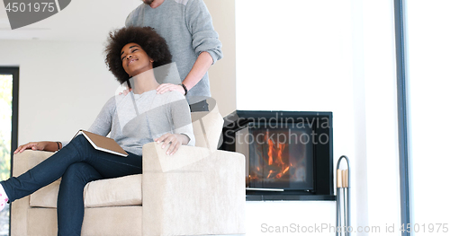 Image of multiethnic couple hugging in front of fireplace