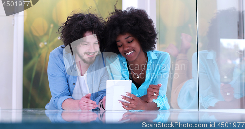 Image of Couple relaxing together at home with tablet computer