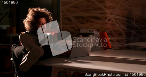 Image of businessman sitting with legs on desk at office