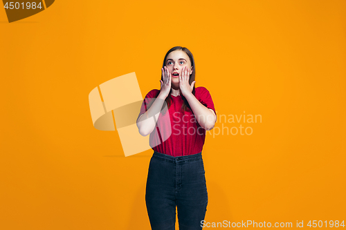 Image of Beautiful teen girl looking suprised isolated on orange