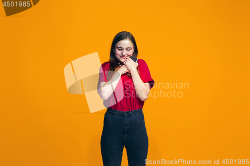 Image of The happy teen girl standing and smiling against orange background.