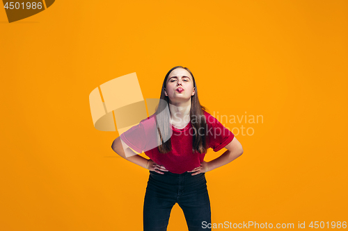 Image of The happy teen girl standing and smiling against orange background.