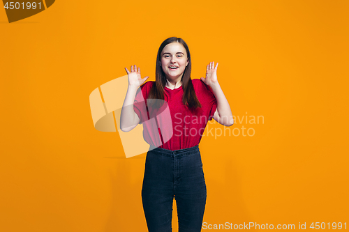 Image of The happy teen girl standing and smiling against orange background.