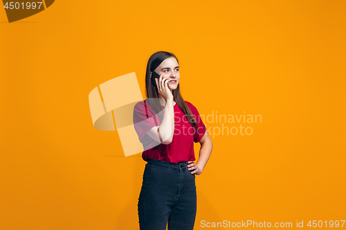 Image of The happy teen girl standing and smiling against orange background.