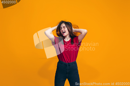 Image of The happy teen girl standing and smiling against orange background.