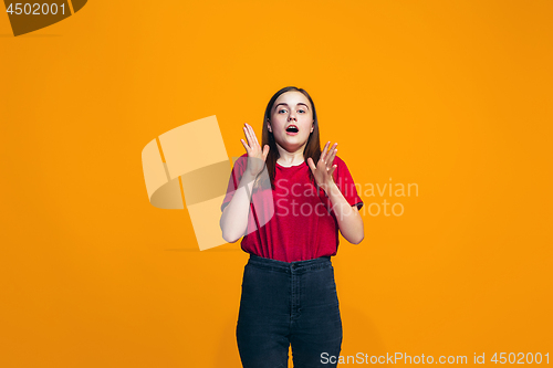 Image of Beautiful teen girl looking suprised isolated on orange