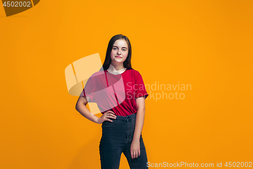 Image of The happy teen girl standing and smiling against orange background.