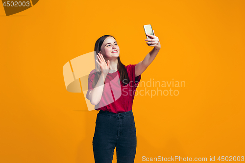 Image of The happy teen girl standing and smiling against orange background.