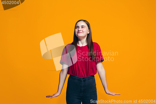 Image of The happy teen girl standing and smiling against orange background.