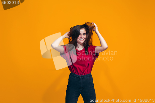 Image of The happy teen girl standing and smiling against orange background.