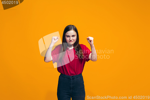 Image of Portrait of angry teen girl on a orange studio background