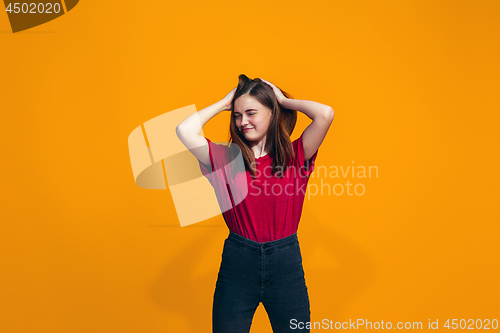 Image of The happy teen girl standing and smiling against orange background.
