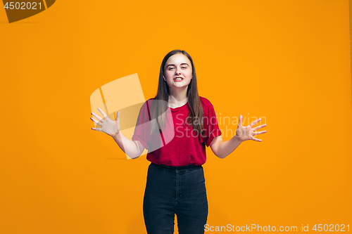 Image of The happy teen girl standing and smiling against orange background.