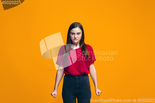 Image of Portrait of angry teen girl on a orange studio background