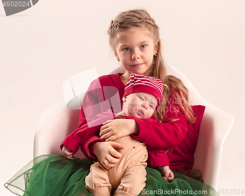 Image of Happy little teen girl holding his newborn baby little sister. Family love.